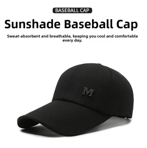 Detail shot of black baseball cap with metallic letter M emblem and long brim visor