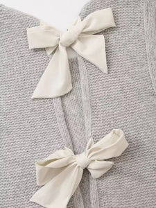 Détail du tissu en maille grise montrant la texture et les nœuds en satin blanc