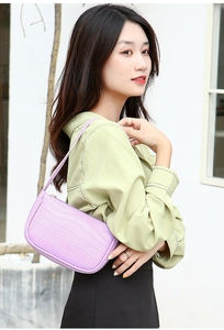 Side view of woman wearing a purple crocodile pattern hobo bag against a minimalist wall