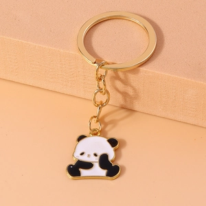 Close-up of golden panda keychain with black and white enamel detail on matte surface