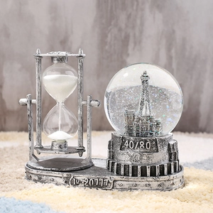 Detail of vintage hourglass and Eiffel Tower crystal ball on a metallic industrial base
