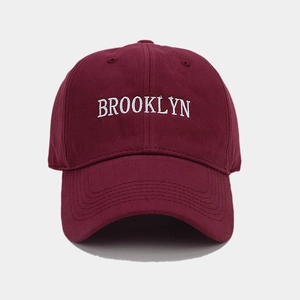Detail of white Brooklyn embroidery on a burgundy cotton twill baseball cap