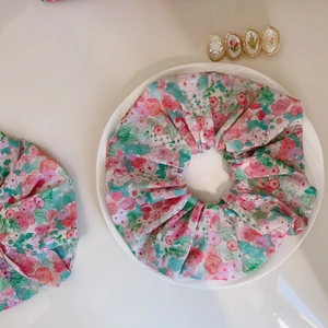 Macro detail of floral cotton scrunchies with pink and green patterns on white plate