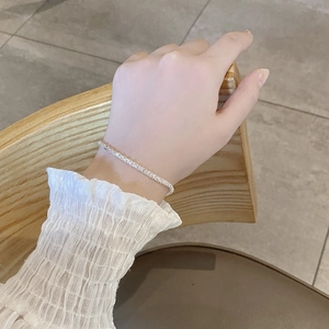 Close-up of a sparkling S925 sterling silver feather chain bracelet on a woman's wrist