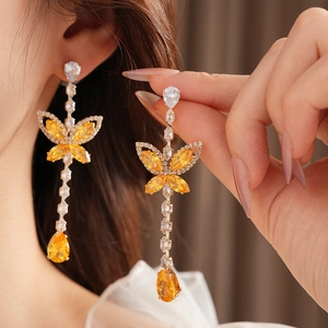 Detail of butterfly drop earrings with yellow teardrop stones on gold-plated metal