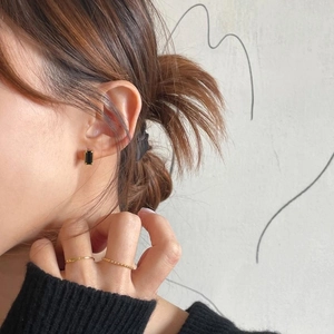 Detail of elegant black gemstone earrings and slim gold rings on a female model