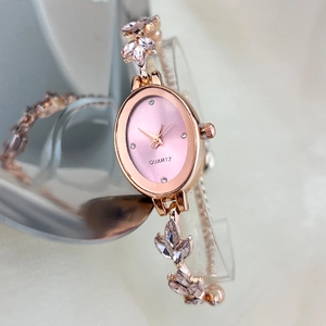 Close-up of oval quartz watch with rose gold bracelet and pink crystal leaf accents