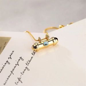 Detailed view of a golden Evil Eye cylindrical pendant with blue inlay on a gift card