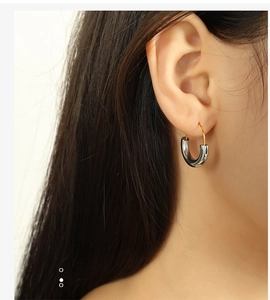 Close-up of two-tone silver U-shaped hoop earrings with gold hooks on a model