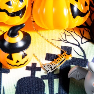 Detail of Natalia name necklace with orange Halloween pumpkin finish and silver chain