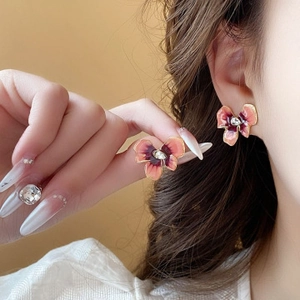 Gros plan de boucles d'oreilles fleurs avec dégradé rose et violet et bords dorés