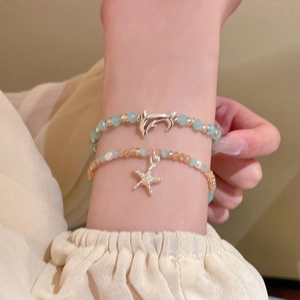 Detail von Perlenarmbändern mit Delfin- und Seesternanhängern in Blau und Rosa