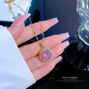 Macro detail of gold necklace featuring a round pink crystal pendant with a halo of diamonds