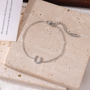 Silver horseshoe U-shaped stainless steel bracelet with cubic zirconia on travertine stone