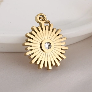 Detailed close-up of a gold sunburst gear pendant with a clear zircon stone on a ceramic dish