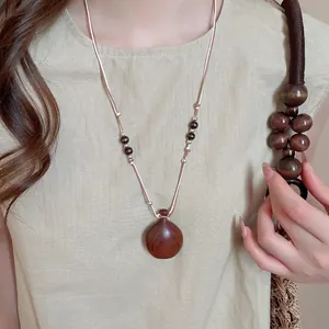 Retro wooden bottle pendant necklace with wax rope and beads on a linen shirt model
