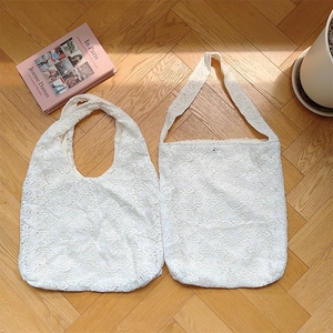 Détail du sac cabas en dentelle blanche sur parquet avec lumière naturelle et ombre