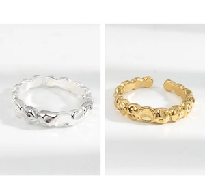 Dettaglio di anelli con trama martellata in oro e argento con design aperto regolabile