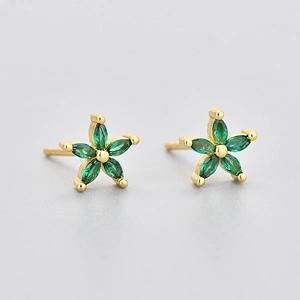 Detailed view of flower studs with green marquise stones in a gold setting
