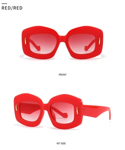 Detail view of irregular red polygon sunglasses with golden metallic accents