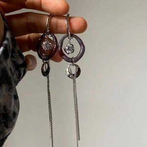 Close-up of long tassel earrings with purple resin rings and sparkling crystal studs