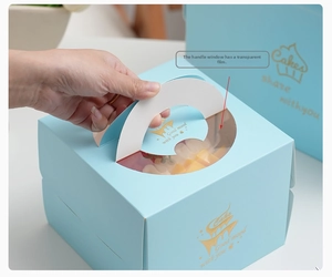 Detail of light blue cake box with golden foil lettering and clear protective window