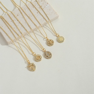 Golden vintage cross pendant necklace with zircon stones on a beige stone surface