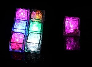 Macro shot of colorful LED ice cubes glowing on a reflective black surface