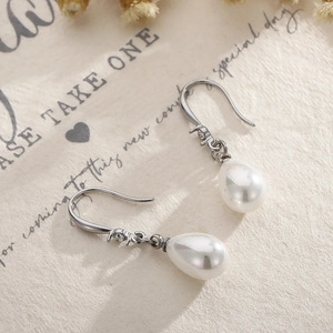 Détail de boucles d'oreilles en perles argentées avec zircons sur papier rétro