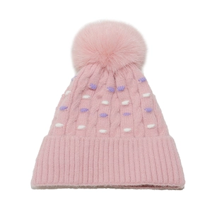 Primer plano del gorro de punto rosa con pompón suave y motivos de puntos lilas