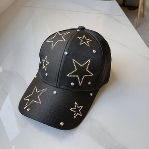 Black baseball cap with rhinestone star design on a smooth marble background surface