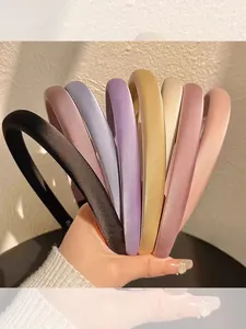 Close-up of seven assorted colorful satin padded headbands held in hand for hair styling
