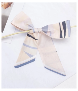 Close-up of a large satin hair scarf featuring blue and beige abstract stripe patterns