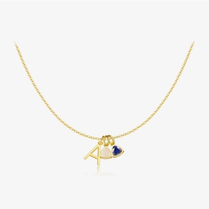 Detail of gold necklace featuring letter A and triangular blue and white gemstones