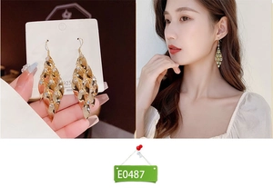 Detailed close-up of golden leaf tassel earrings with white zircons on 925 silver hooks