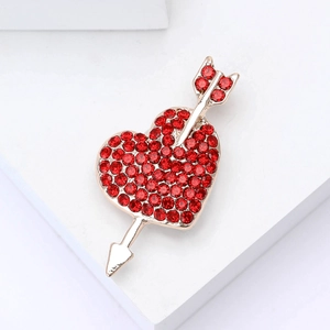 Golden heart arrow brooch featuring red rhinestones on a minimalist white background