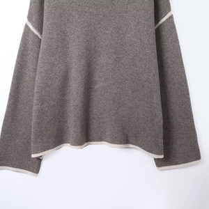 Detailed view of dark grey knit sweater with white contrast trim on the hem and cuffs