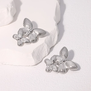 Macro shot of silver butterfly earrings with detailed radial wing textures on stone