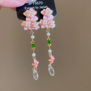 Detailed shot of floral pearl earrings featuring pink butterflies and crystal teardrops