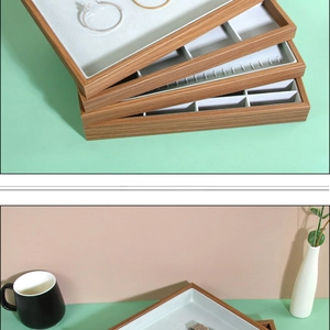 Close-up of stackable wood grain jewelry trays with grey velvet slots for rings and watches