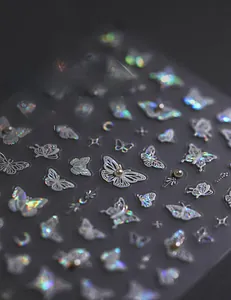 Macro view of holographic laser nail stickers with butterfly, star, and pearl details