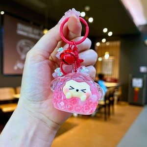 Detail shot of a cute pink liquid sand keychain with a cartoon animal and a red bell