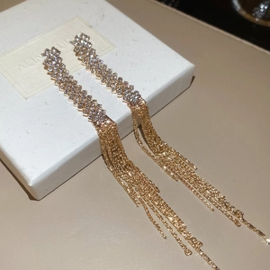 Close-up of golden tassel earrings with sparkling rhinestones and long chain fringe