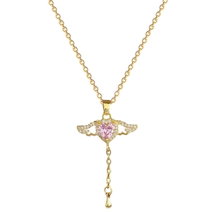 Elegant gold wing necklace featuring a pink heart stone and tassel pendant on white background