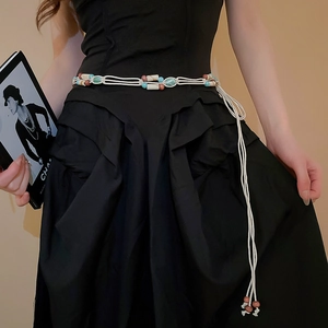 Detail van bohemien geweven tailleketting met veelkleurige kralen en franjes op zwarte jurk