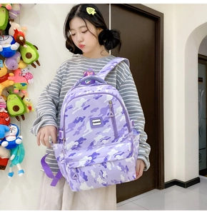 Detail showing the purple camo backpack with fashion rubber patch and multiple zip pockets
