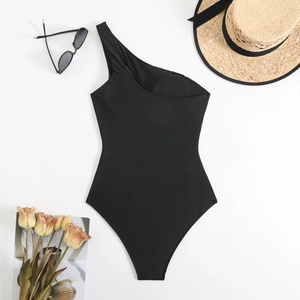 Detail of black one-shoulder swimsuit with built-in pads and summer beach accessories