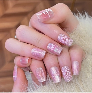 Close-up of pink gradient press-on nails with bow designs and white butterflies on fur