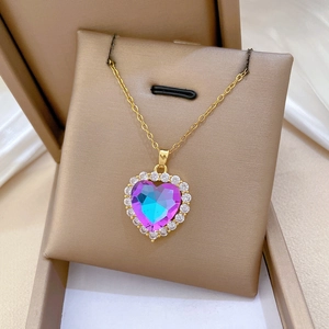 Detail of gold heart pendant with blue-purple gradient gem in a brown jewelry gift box