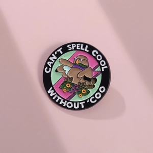 Detail showing round enamel owl pin with Can't spell cool without coo text on pink surface